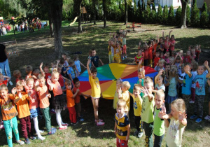 dzieci stoją przy kolorowej chuście ubrane jesienne barwy